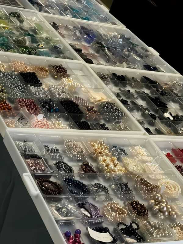 Boxes filled with assorted beads and pearls organized by color and size.